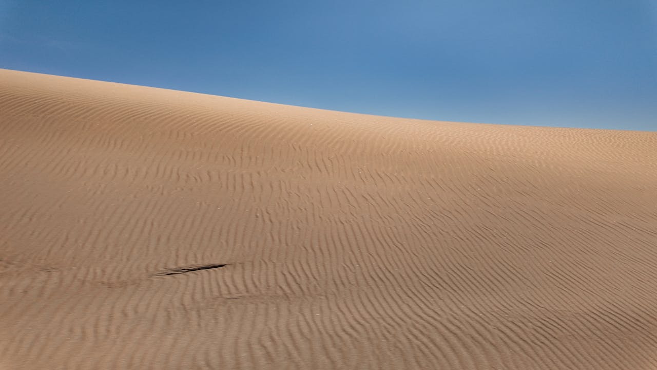 Twój bałagan to nie jest brak charakteru. To jest wiadomość. A breathtaking view of the Namibian sand dune under a clear blue sky, showcasing the beauty of the desert landscape.